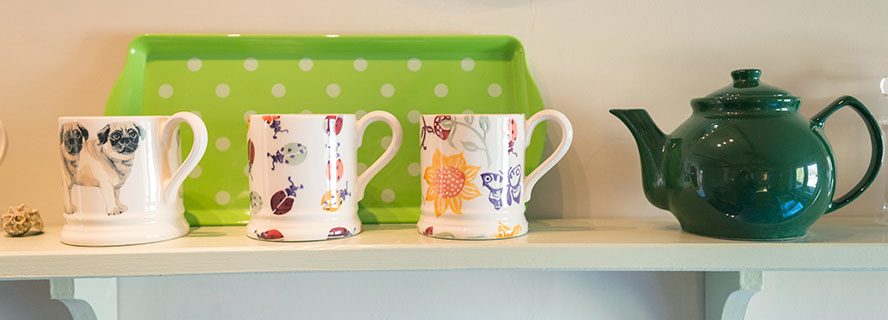 Mugs and teapot on shelf at holiday cottage